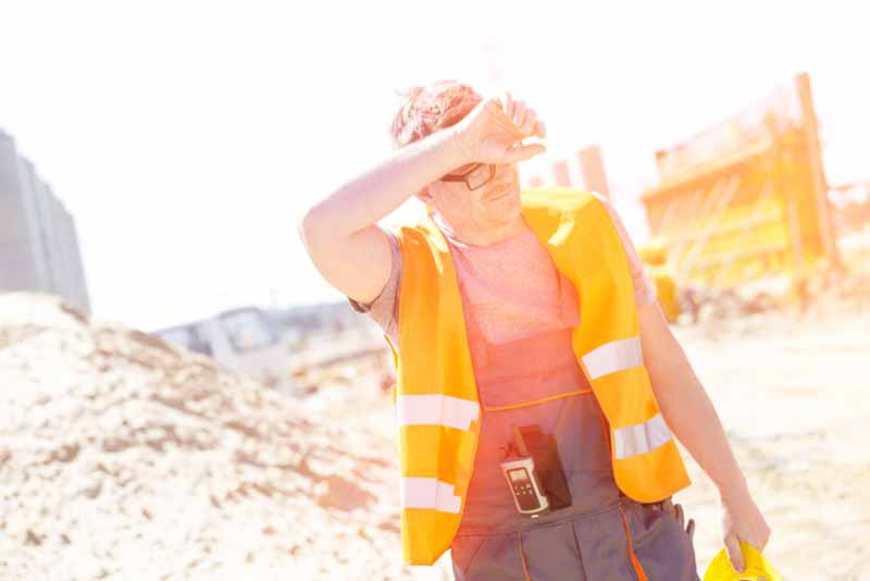 worker in high visibility workwear wiping his brow with his arm from the heat