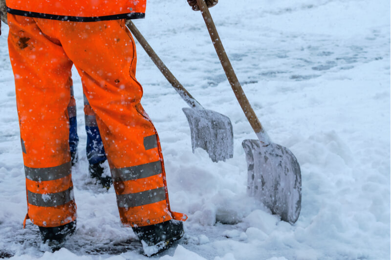 men in high visibility workwear shovelling snow