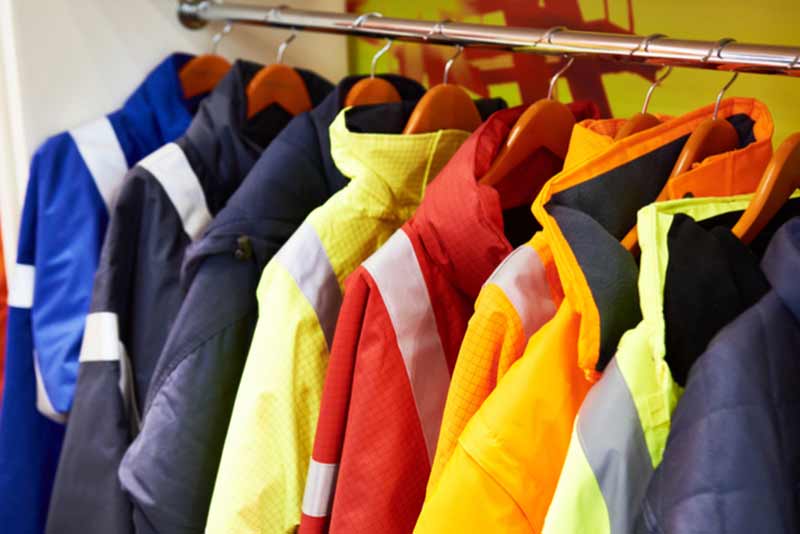 different coloured workwear jackets hanging up on coat hangers in a line