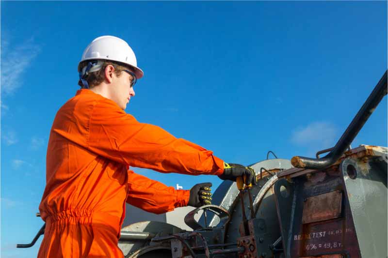 work man in orange high visibility workwear operating heavy machinery 