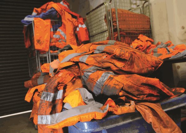 orange high visibility workwear on coat hanger hanging in a line