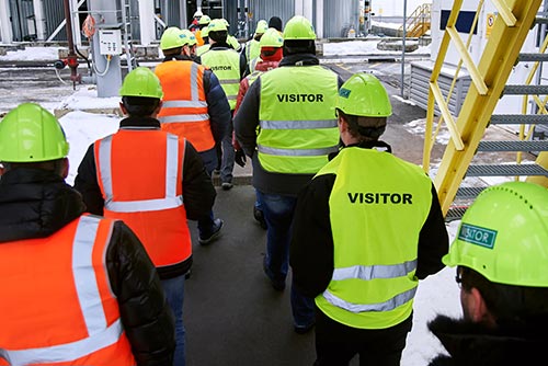 phs besafe large group of men wearing yellow hard hats and hi viz vests walking into a building site